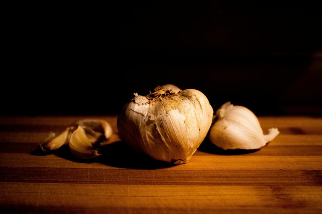 A dramatic close-up of a garlic bulb on a wooden cutting board with warm lighting, ideal for culinary themes.
