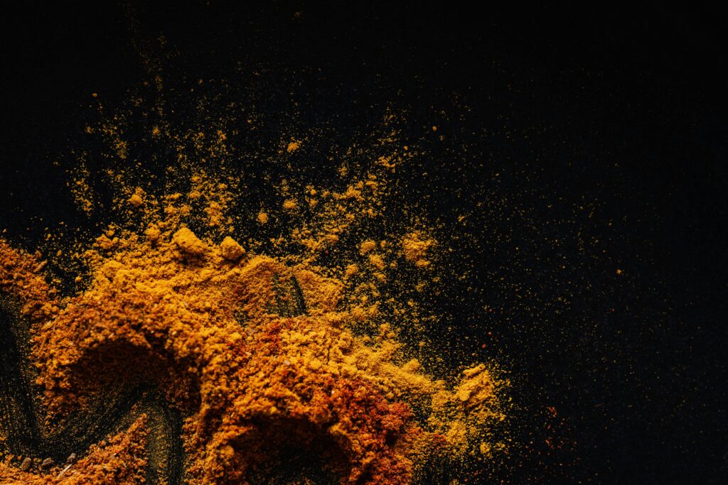The Benefits Of Tumeric Colorful and aromatic spices spilled on a dark surface, showcasing culinary diversity.