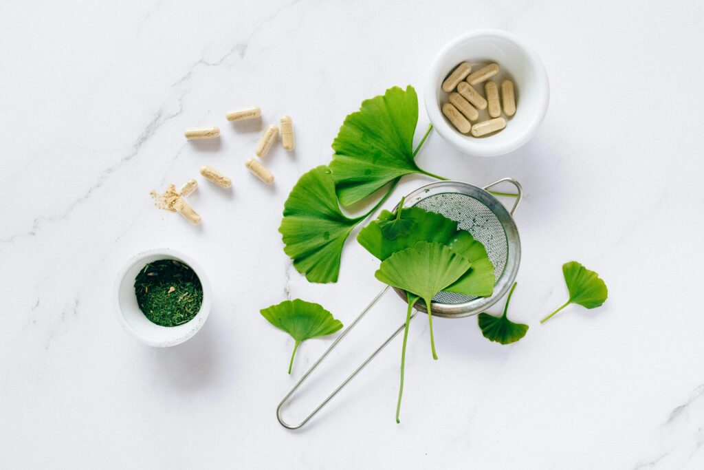 Health benefits of Ginkgo Biloba Flat lay of ginkgo leaves, capsules, and herbal powder on marble for natural health remedy.